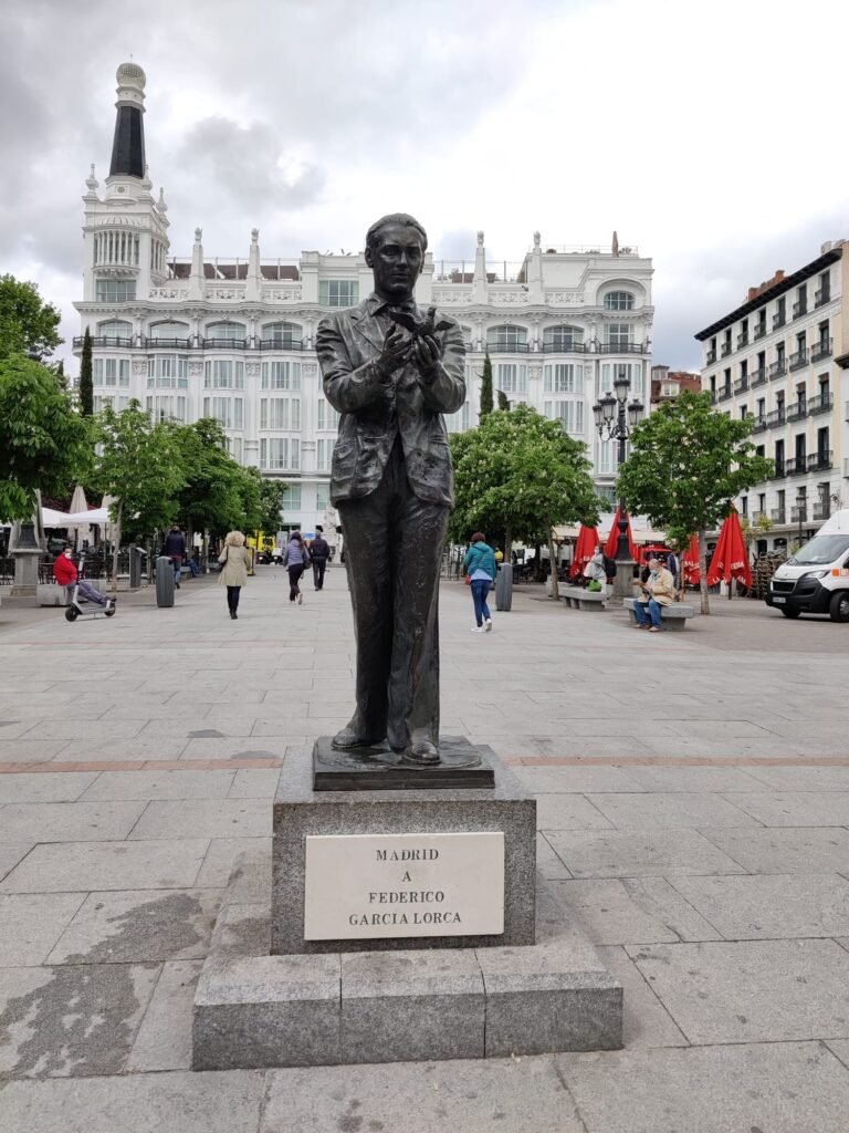 Estatua de Lorca sujetando una alondra entre las manos y acompañado de una placa que indica: "Madrid a Federico García Lorca".