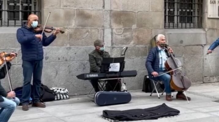 Cinco músicos callejeros tocando instrumentos como el piano y el violín a las puertas de la Academia de Bellas Artes de San Fernando