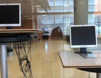 Biblioteca de una universidad con dos monitores de ordenadores