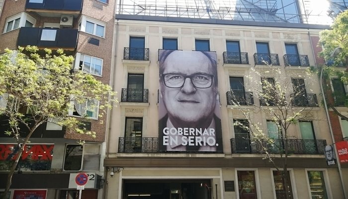 Pancarta política de PSOE extendida en la fachada de un edificio donde se ve un primer plano de Ángel Gabilondo y se lee "gobernar en serio".