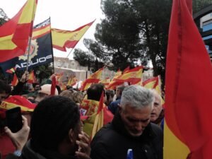 Imagen de banderas de España y una de la Policía Nacional elevadas por las personas en una manifestación de Vox.