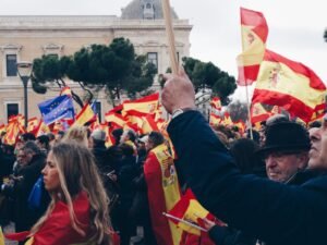 Imagen de banderas de España y una de la Unión Europea elevadas por las personas en una manifestación de Vox.