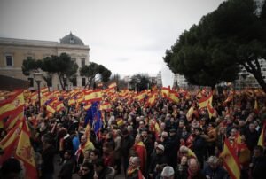 Multitud de personas desde un ángulo alto, levantando banderas de España y una de la Unión Europea en una manifestación de Vox.