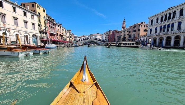 Una embarcación de madera amarilla navegando por uno de los canales de Venecia