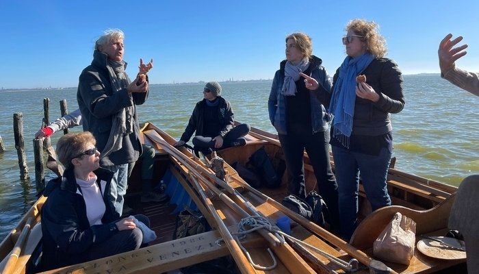 Un grupo de mujeres habla entre si y de pie en sus embarcaciones en Venecia