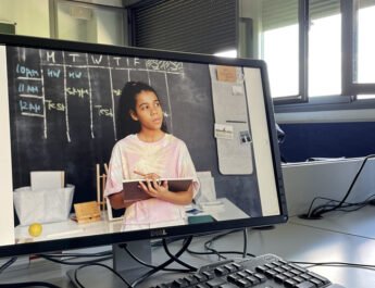 Dos pantallas de ordenador en una clase de universidad con una foto de una estudiante proyectada en la pantalla de uno de ellos