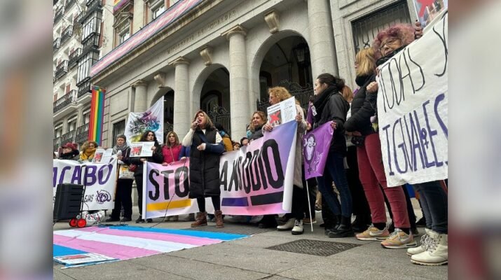 Concentración de personas trans con banderas en tonos rosas y celestes pastel y Mar Cambrollé, la representante de la Asociación de Transexuales de Andalucía- Sylvia Rivera, en el centro pronunciando un discurso en la Madrid, a 9 de enero de 2024.
