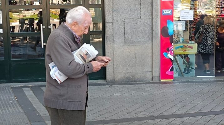 Pensionista en la calle mirando el teléfono