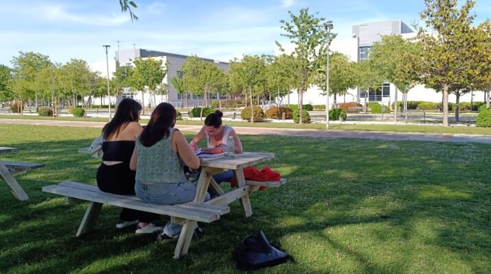 Grupo de chicas conversando en una mesa exterior de la Universidad Rey Juan Carlos, en el campus de Fuenlabrada.
